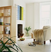 Movable shelving unit in living room with white painted floorboards and throw over sofa