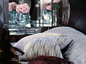 Patterned cushions on silver bed cover