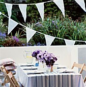 Striped patio tablecloth with bunting and purple flowers