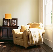 Gelber Sessel und Decke in einer Zimmerecke mit Holzanrichte und Schiebefenster