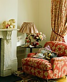 Colourful floral patterned fabrics on armchair and curtains in room corner with dog sleeping