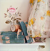 Well read books on shelf with floral wallpaper and curtains