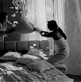 Ein Paar liefert sich eine Kissenschlacht auf einem Bett in einem Schlafzimmer