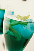 Highland Fling Cocktail aus Blue Curacao Orangenlikör, Whiskey, Bitters und Sodawasser, garniert mit Kiwischeiben und Früchten