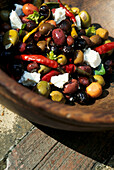 Olives with feta cheese and chillies in a wooden bowl