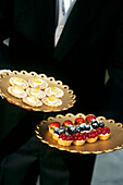 Kellner serviert Dessert-Canapes und Obsttörtchen