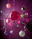Close up of colourful Christmas baubles against pink background