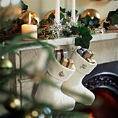 Close up of white felt Christmas stockings filled with tiny presents on marble mantlepiece