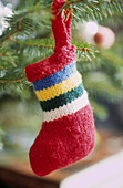 Close up of tiny hand knitted stripey stocking on Christmas tree