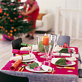 Weißes Wohnzimmer mit einem farbenfrohen, orange- und rosafarbenen, weihnachtlich gedeckten Tisch mit orientalischen Motiven