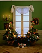 Weihnachtsbäume mit brennenden Kerzen und herzförmigen Ornamenten geschmückt
