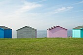 Four Colourful beach huts in a row at Whitstable in Kent with blue skies and sea view