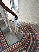 Striped carpet on staircase with wooden handrail