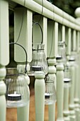 Glass lanterns hanging from a pale green wooden ballustrade in the garden
