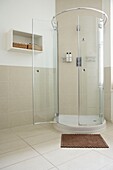 Curved shower with glass doors in stone tiled bathroom