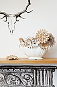 Paper flowers in bowl on mantlepiece with drawing of animal head