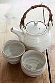 Pottery teapot and cups on wooden tabletop