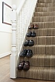 Men's shoes paired on carpeted staircase  London  England