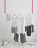 White clothing hangs from clothes rail dripping with grey paint