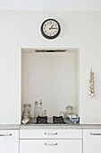Storage jars and recessed hob below clock in London kitchen   UK
