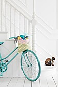 Turquoise painted bike with Easter eggs and rabbit on white painted staircase in family home