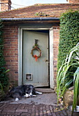 Hund liegt am verwitterten Eingang eines gemauerten Beneden Cottage, Kent, England, UK