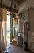 Hutständer mit Gummistiefeln an offener Tür eines Bauernhauses aus Stein, Dordogne, Frankreich