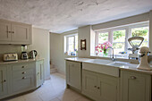 Cut flowers on windowsill in fitted Kent kitchen with double sink  England  UK
