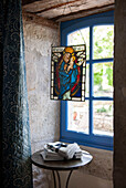 Buntes Glas hängt in einem blau gestrichenen Fenster einer umgebauten Steinscheune in Lotte et Garonne, Frankreich