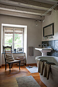 Chair at window with pedestal basin and freestanding bath in Dordogne farmhouse  Perigueux  France