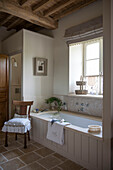 Chair beside bath at window in beamed Dordogne farmhouse  Perigueux  France