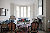 Pair of checked vintage chairs in living room with bay window in South Kensington townhouse  London  UK
