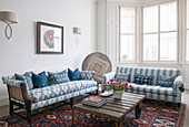 Blaues und weißes Sofa mit Schnittblumen auf niedrigem Couchtisch in einem Wohnzimmer in South Kensington London UK