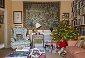 Gifts under Christmas tree with wall tapestry in London living room  England  UK