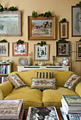 Holly leaves on framed artwork above yellow sofa in London home  England  UK