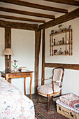 Antique furniture and wall mounted shelf with folded quilts in High Halden cottage  Kent  England  UK
