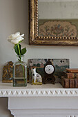 Single stem rose and ornaments with gilt framed mirror on mantlepiece in East Barsham cottage  Norfolk  England  UK