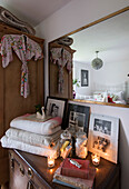 Lit tealights with folded blankets and family photographs below large mirror in Kilndown cottage  Kent  England  UK