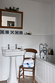 Folded towels on wooden chair in tongue and groove bathroom in Kilndown cottage  Kent  England  UK