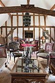Vintage armchairs and glass topped coffee tables in timber farmed living room of Suffolk home  England  UK