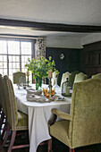 Lime green velvet dining chairs with cut flowers on table in Suffolk farmhouse  England  UK