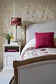 Goldener und roter Lampenschirm am Bett in einer umgebauten Scheune in Norfolk aus dem 18