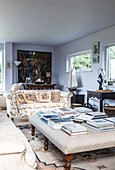 Books on ottoman in light blue living room of Norfolk coastguards cottage  England  UK