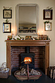 Lit woodburner with framed embroidery and Christmas decorations in East Sussex coach house  England  UK