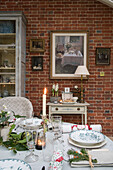 Lit candle on dining table with exposed brick wall in East Sussex coach house  England  UK