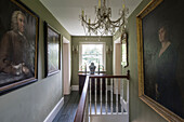 Large artworks and glass chandelier in landing of 18th century Surrey home  England  UK