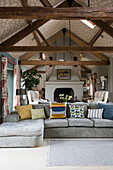Light grey sofa with cushions in Oxfordshire barn conversion with wallpapered ceiling  England  UK