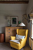 Yellow wingback armchair and wooden chest of drawers in Oxfordshire barn conversion  England  UK