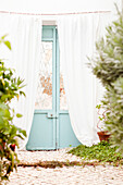 Light blue double door with white curtains in Castro Marim, Portugal