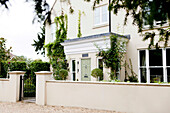 Cream facade of Amberley home with wrought iron gate West Sussex England UK